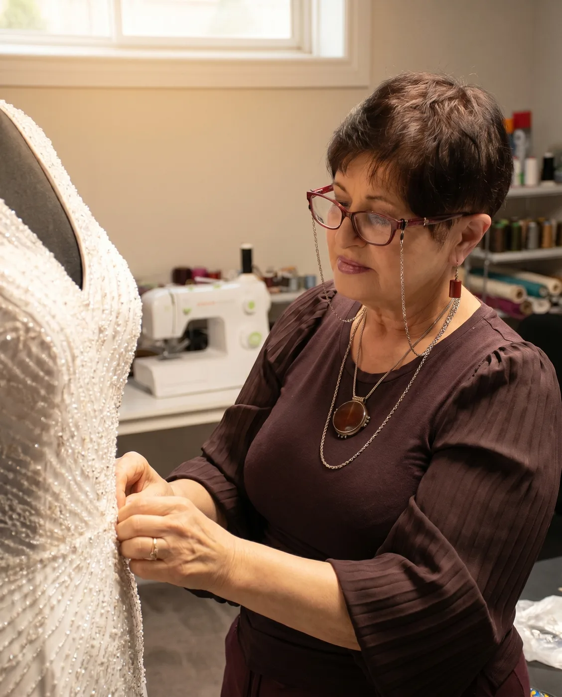 Designer Rita Kleiner hand-pinning a beaded ivory bridal bodice on the dress form in her atelier